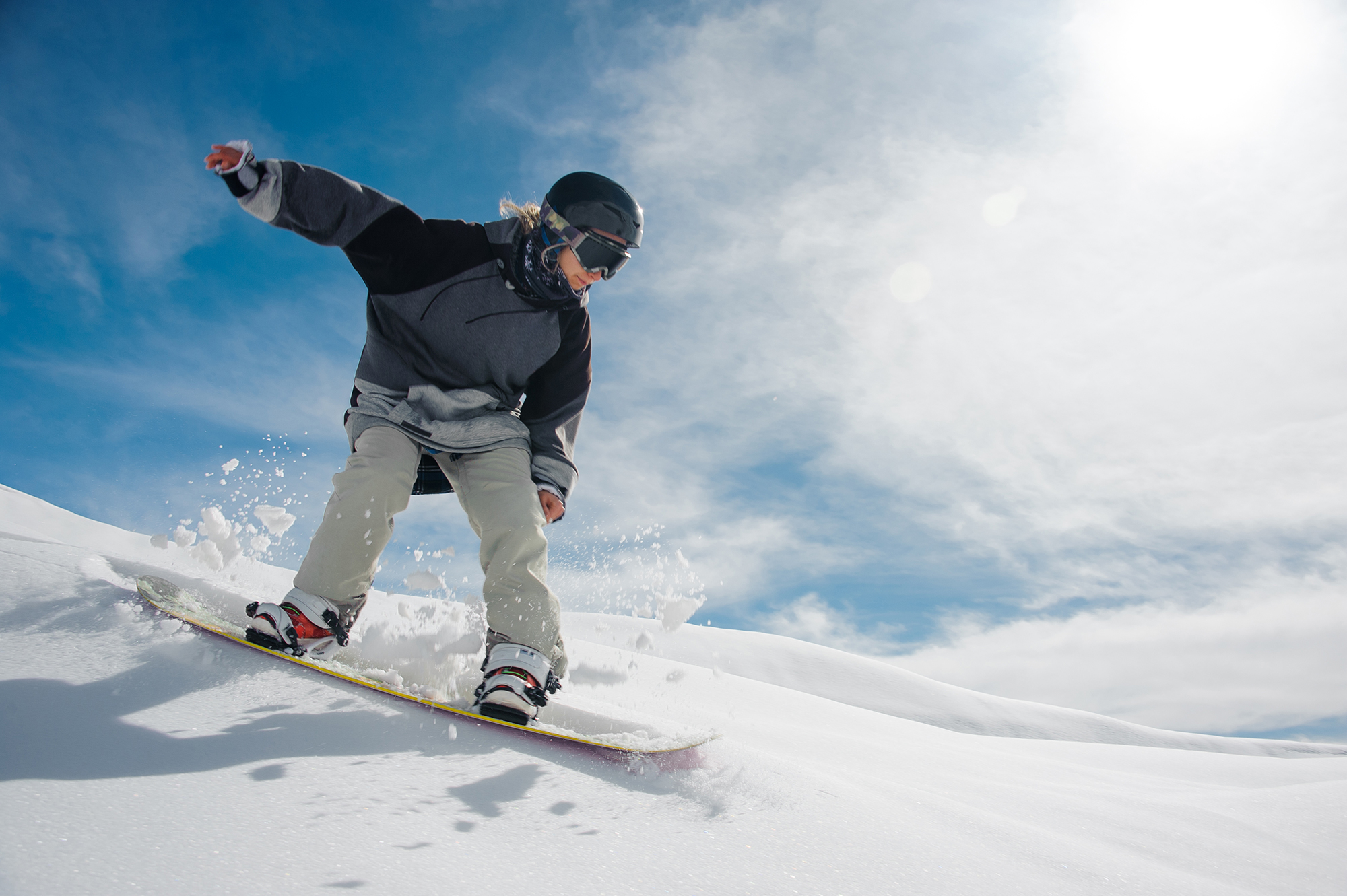 Young female snowboarder running down the mountain slope